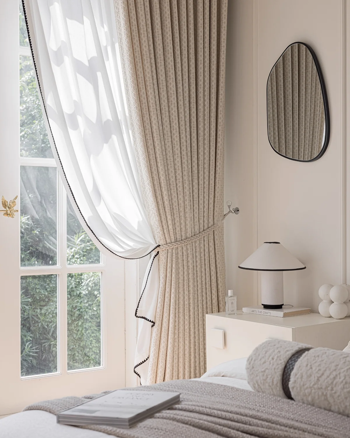 Basketweave texture curtain softly tied back beside a bed, soft woven drapes and sheer layer in a bright modern bedroom.