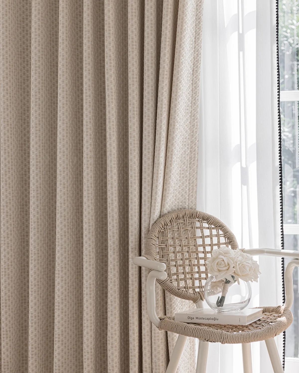 Basketweave texture curtain drawn beside a window with a rattan chair, soft woven drapes in a cozy reading corner.