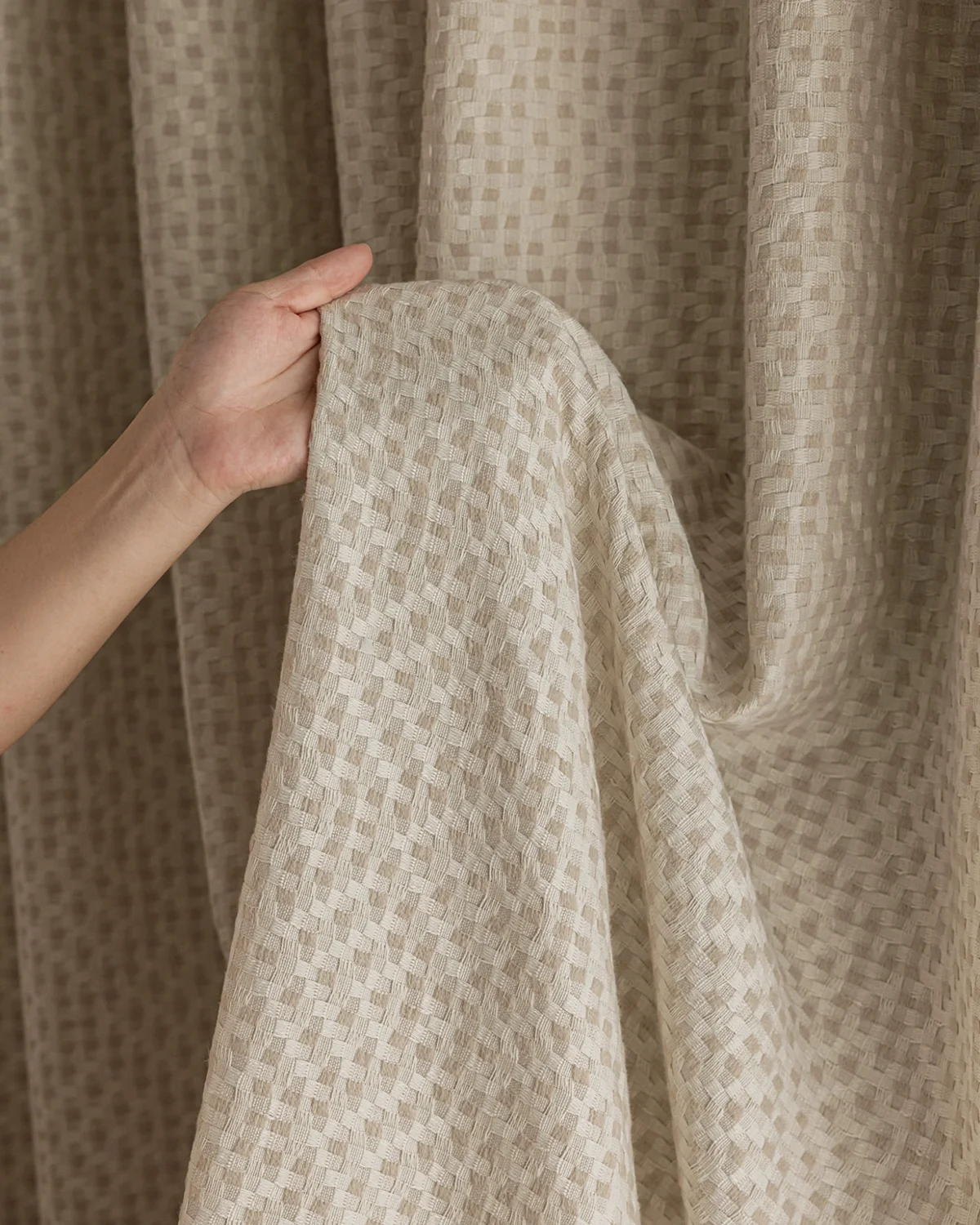 Close-up of basketweave texture curtain fabric, soft woven drapes surface in a neutral tone.