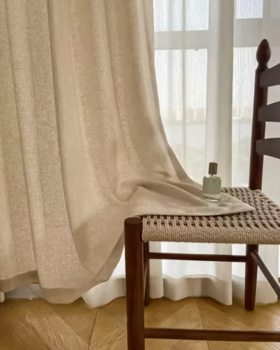 Soft textured curtain fabric hanging by a window next to a wooden chair, showing lattice texture curtain drapes in a modern living room.