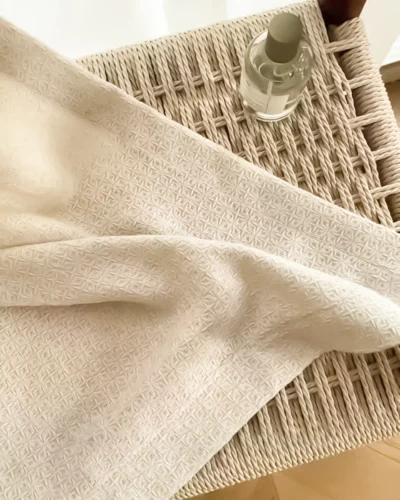 Soft textured curtain fabric with a refined lattice weave, draped over a woven tray – textured curtain fabric detail for custom curtains.