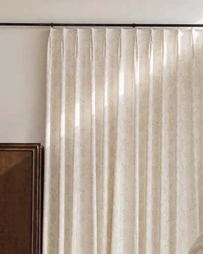 Warm beige floral jacquard blackout curtain hanging in soft pleats.