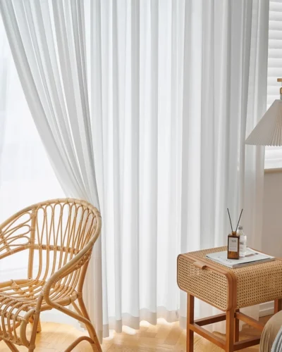 Fine Ridge Texture Curtain in soft matte ivory hanging behind a rattan chair and small wooden side table in a bright living room.