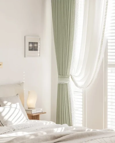 Sage green curtain paired with white sheer curtain in a bright bedroom, floor-length with soft pleats