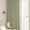 Sage green lace curtain panels in a bright bedroom, floor-length with soft pleats