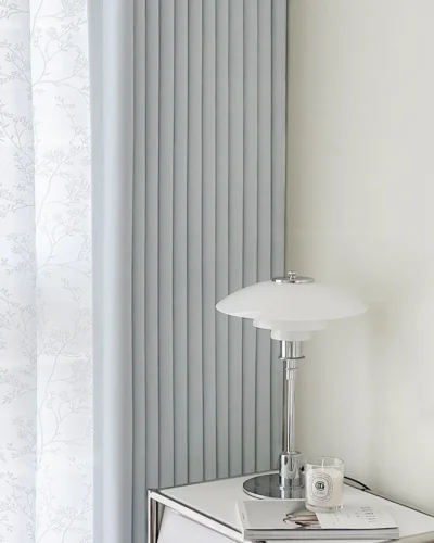 Cool grey blackout curtain in a bright minimalist room with a white table lamp