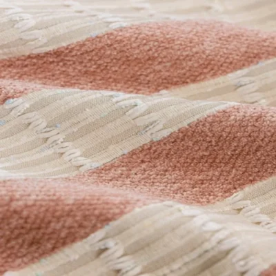 Blush pink and cream striped curtain fabric close-up with confetti speckles and fringe texture