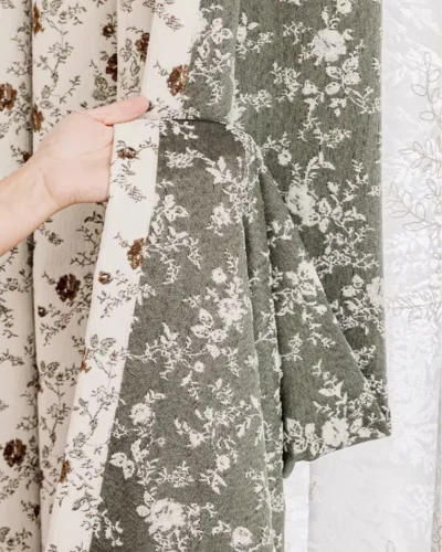 Ivory floral jacquard curtain fabric in Cocoa Bloom shown in hand, vintage floral texture