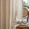 Ditsy floral jacquard sheer curtain in warm beige, light filtering with soft privacy beside a rattan chair