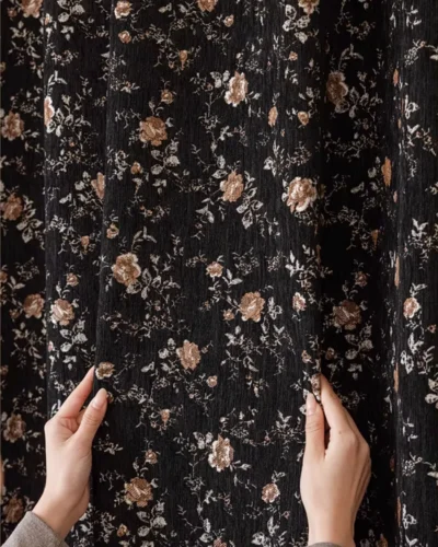 Hands holding Midnight Rose jacquard curtain fabric in Cocoa Bloom, black vintage floral