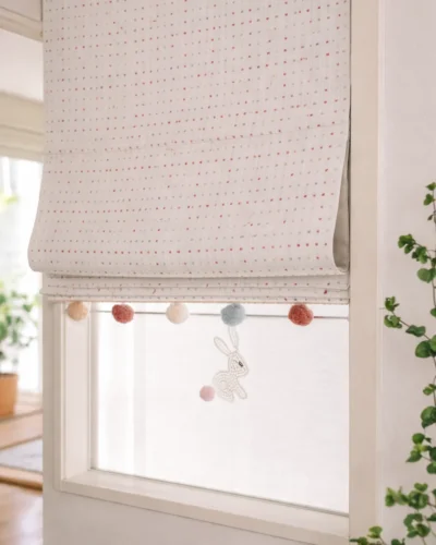 Rainbow Sprinkles Roman Shade installed on a window with pom-pom trim