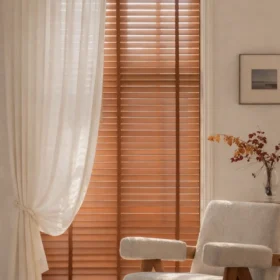 Warm wood venetian blinds in a sunlit living room with sheer curtains