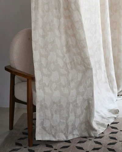 Ginkgo pure linen curtain with botanical leaf pattern beside a wooden chair in a modern interior