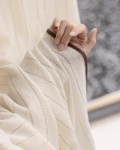 Hand touching the Mocha Pinstripe Sheer Curtain to show its soft texture, flowing drape, and mocha edge detail