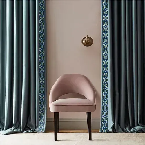 Elegant blue curtains with decorative trim and a pink accent chair in a stylish interior