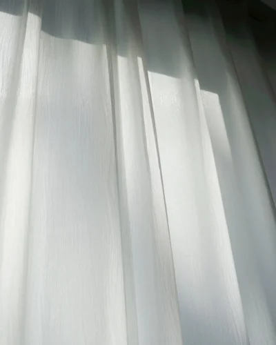 soft white linen texture sheer curtain filtering natural sunlight with soft shadow effect
