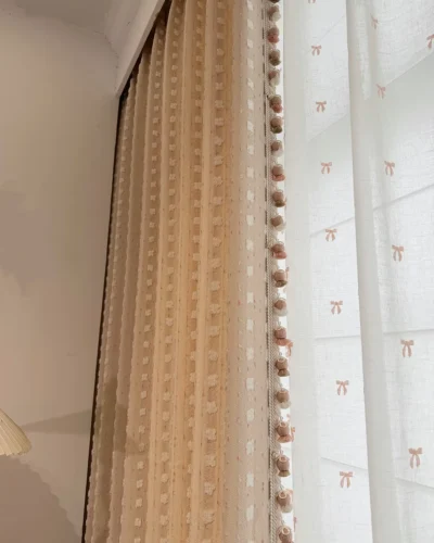 Cotton Candy Cloud Blackout Curtain with soft pink textured fabric, decorative tassel trim and matching sheer curtain.